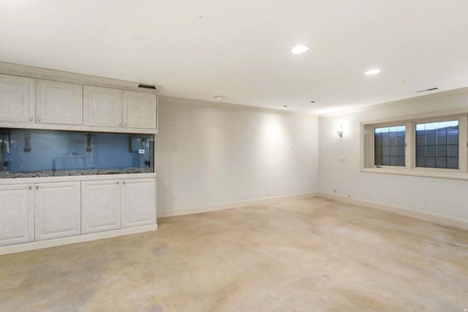 Built-in cabinetry with integrated aquarium, recessed lighting, wall sconces, window with divided lites, and neutral flooring