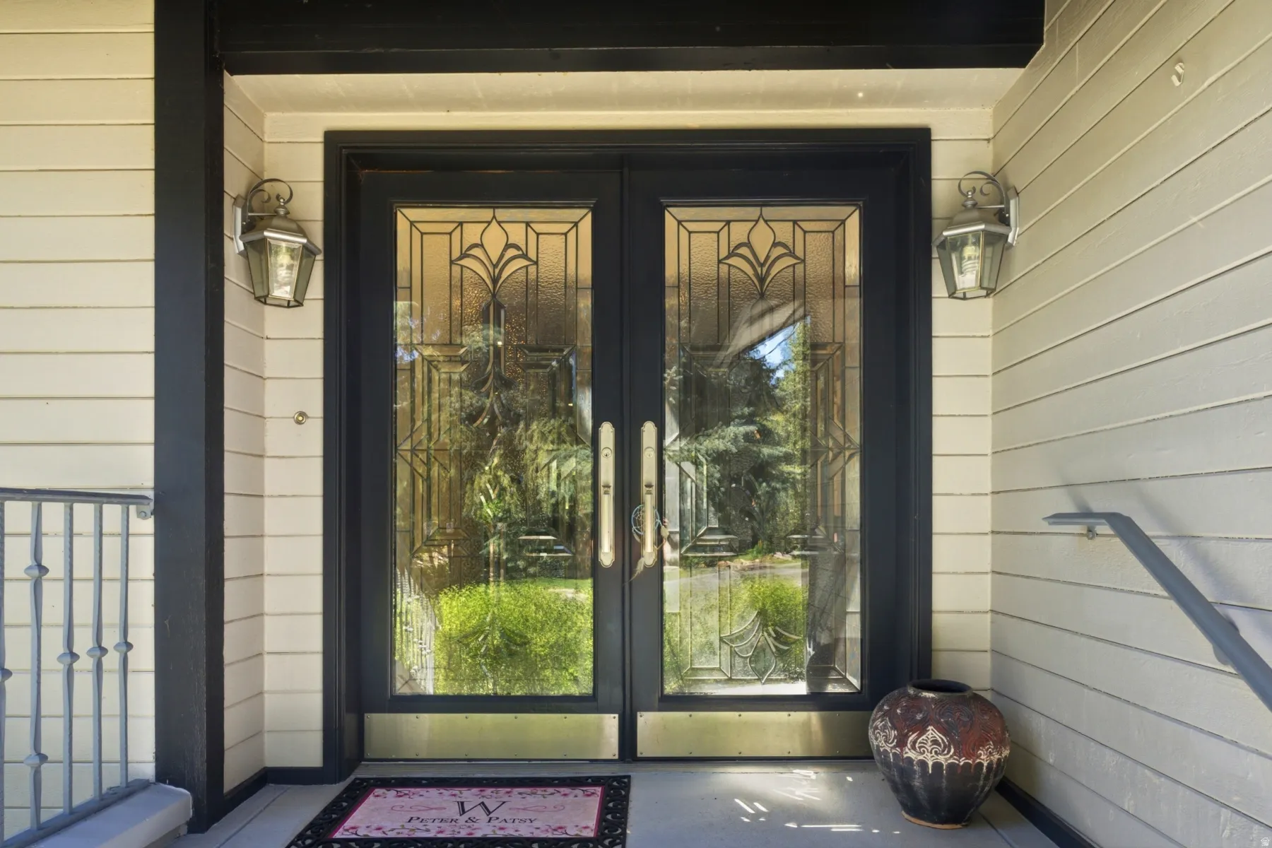 Double entry doors featuring decorative glass panels, brass kick plates, and coordinating hardware