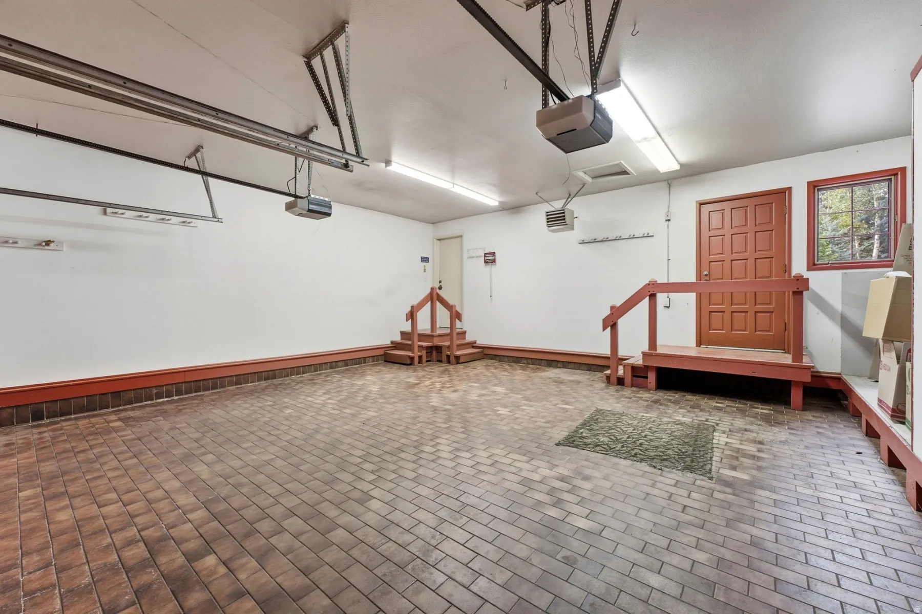 Brick-patterned flooring, red trim, and dual garage door openers