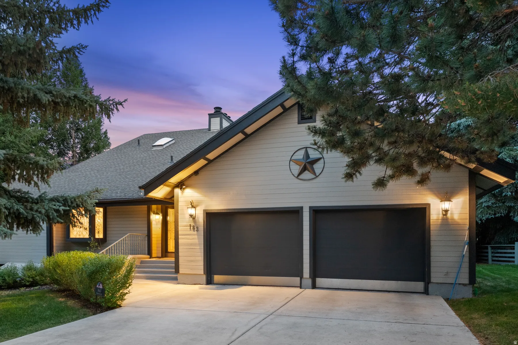 Exterior featuring a concrete driveway, attached garage with two dark doors, and front entry with steps and handrail