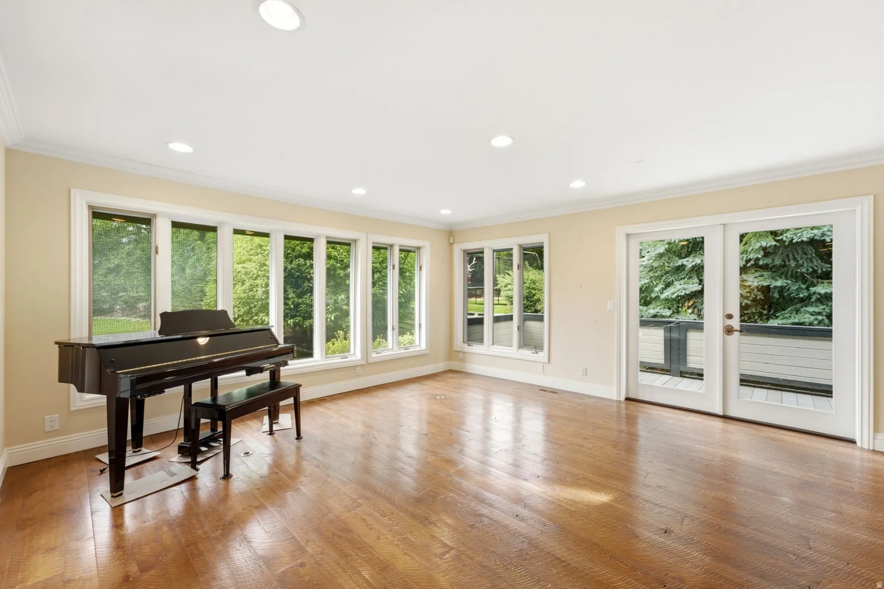 Expansive room with wood-finish flooring, recessed lighting, and a bank of large windows