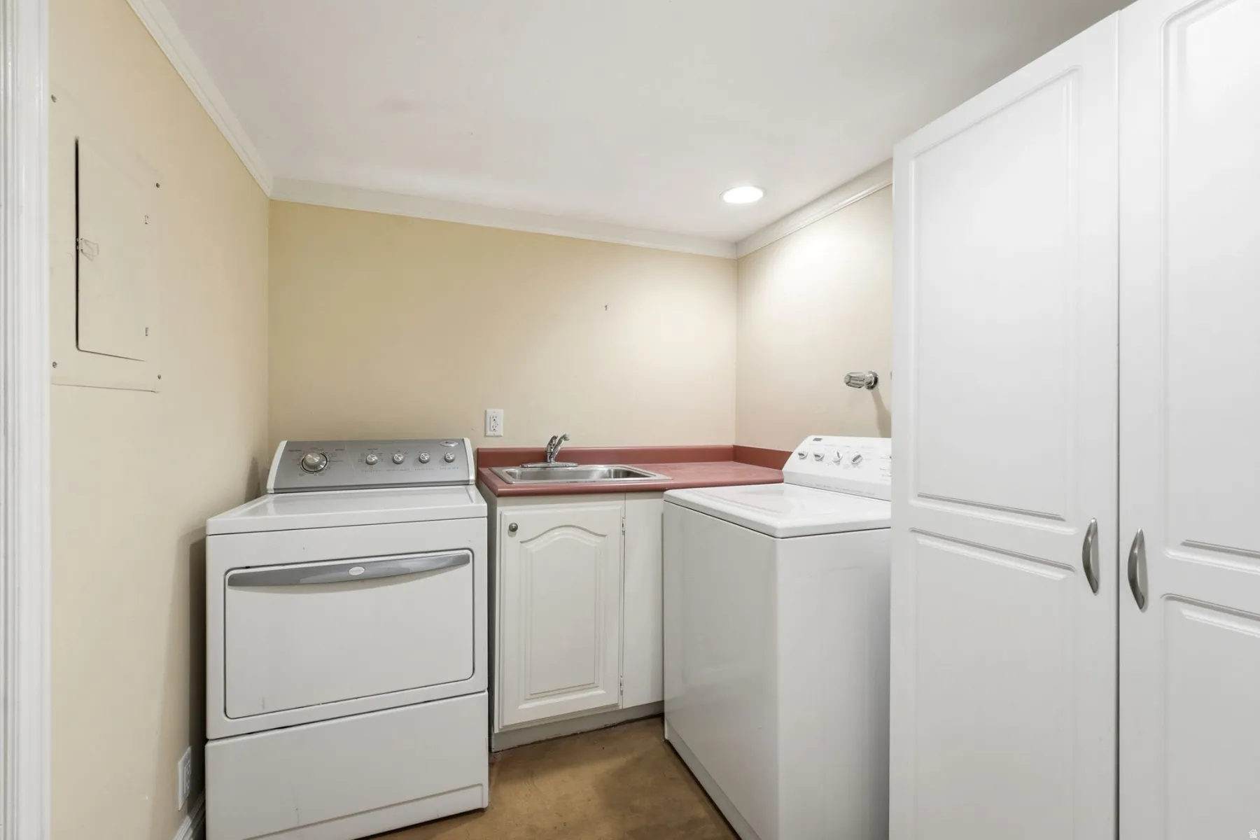 Laundry area featuring extensive built-in cabinetry, a utility sink, and a countertop