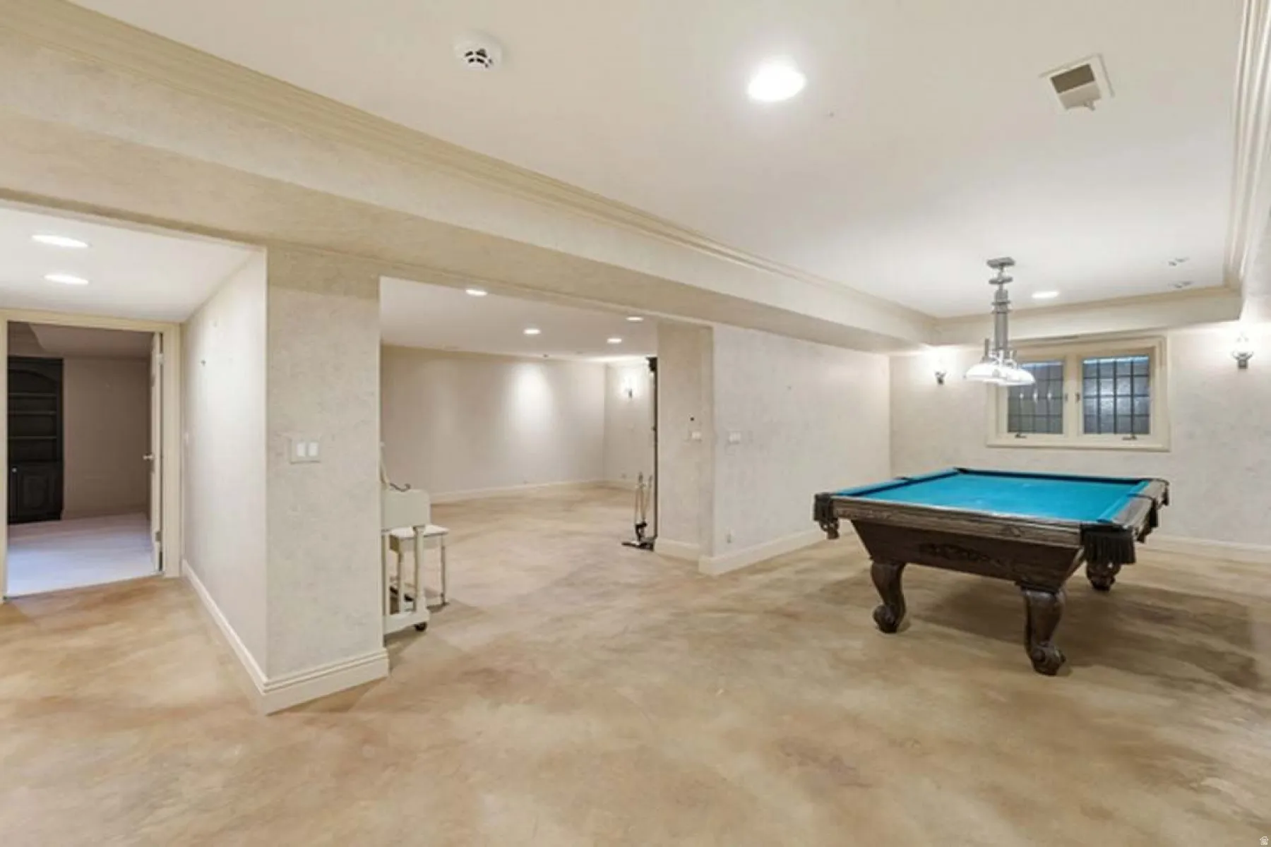 Open-concept lower level featuring a pool table, recessed lighting, wall sconces, and a window with security bars