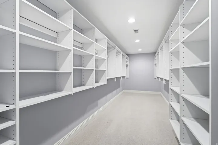 Walk-in closet featuring extensive built-in shelving, hanging rods, recessed lighting, and carpeting