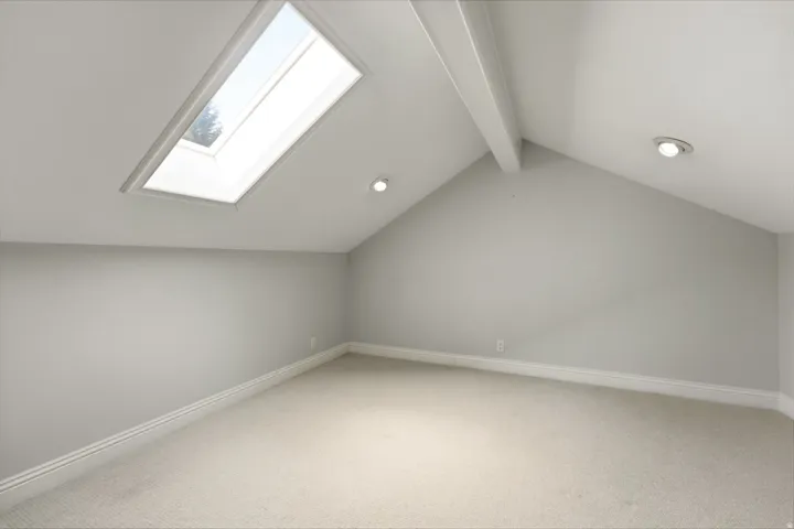 Vaulted ceiling with exposed beam, recessed lighting, skylight, and carpeting