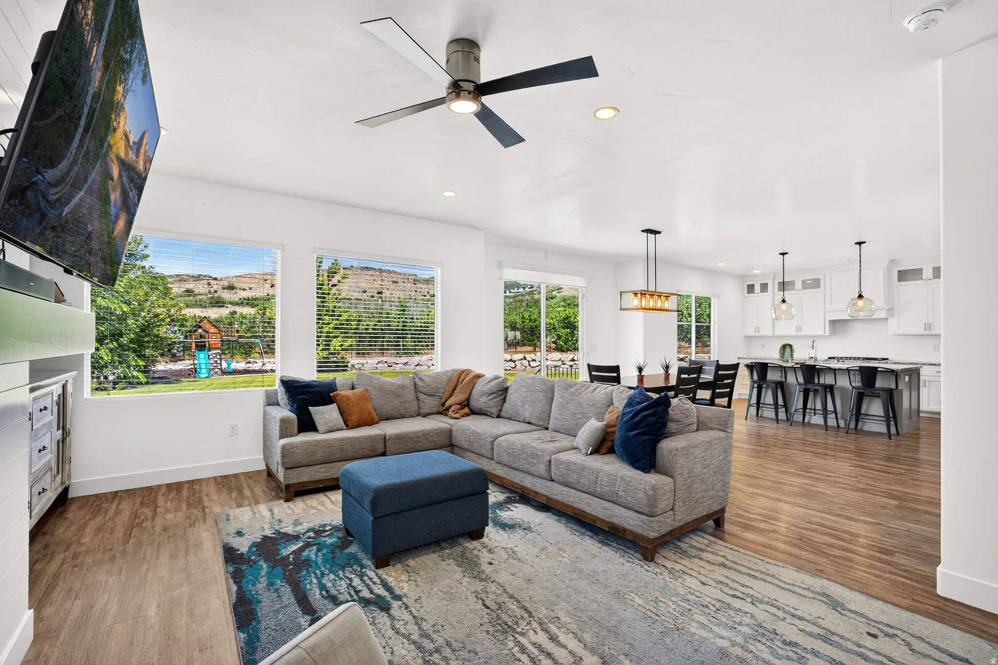 Open-concept living area with wood-finish flooring, recessed lighting, and a modern ceiling fan