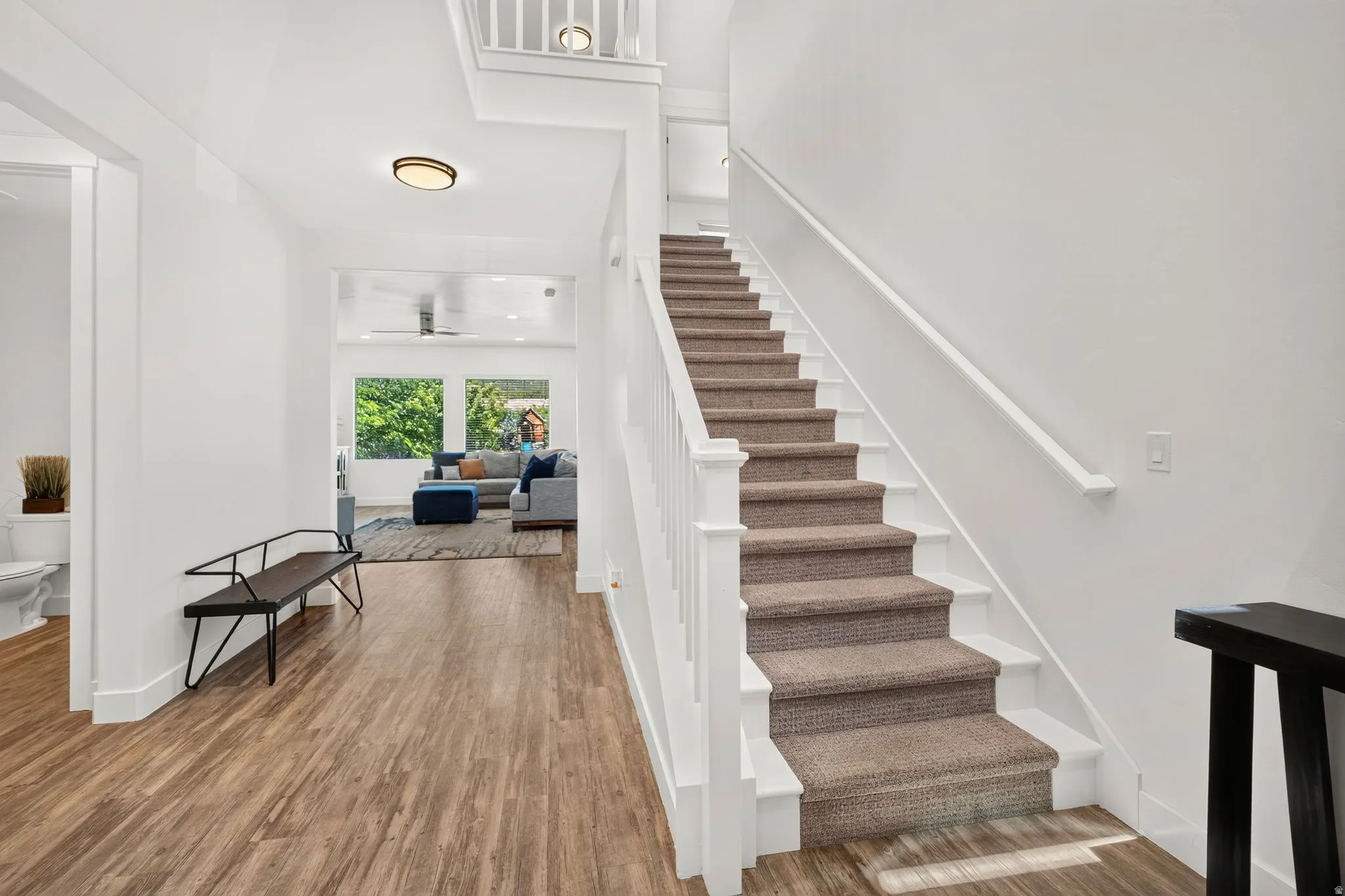 Inviting entryway featuring wood-finish flooring and a carpeted staircase with white risers and railing