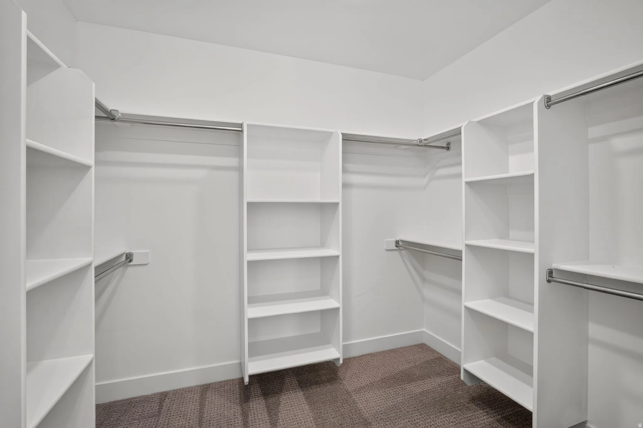 Custom closet system featuring white shelving and chrome hanging rods