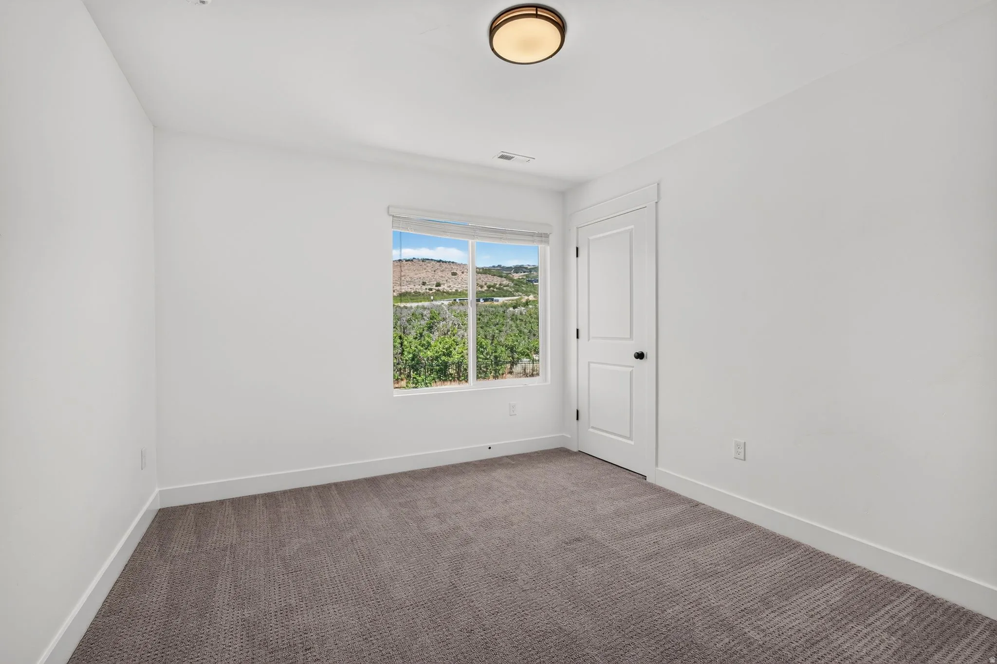 Bright interior space featuring a window with a mountain and tree backdrop