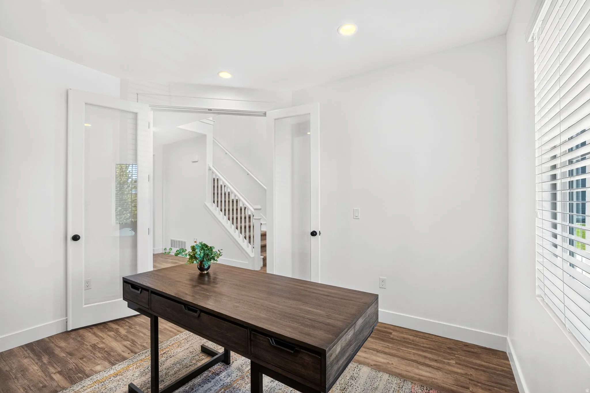 Room featuring white walls, recessed lighting, and wood-finish flooring