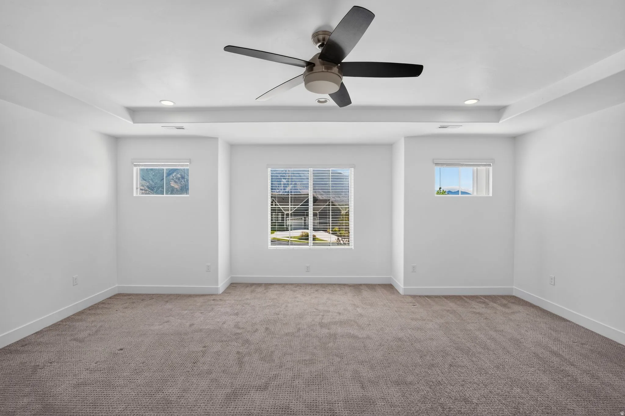 Spacious interior featuring a contemporary ceiling fan, recessed lighting, and tray ceiling detail
