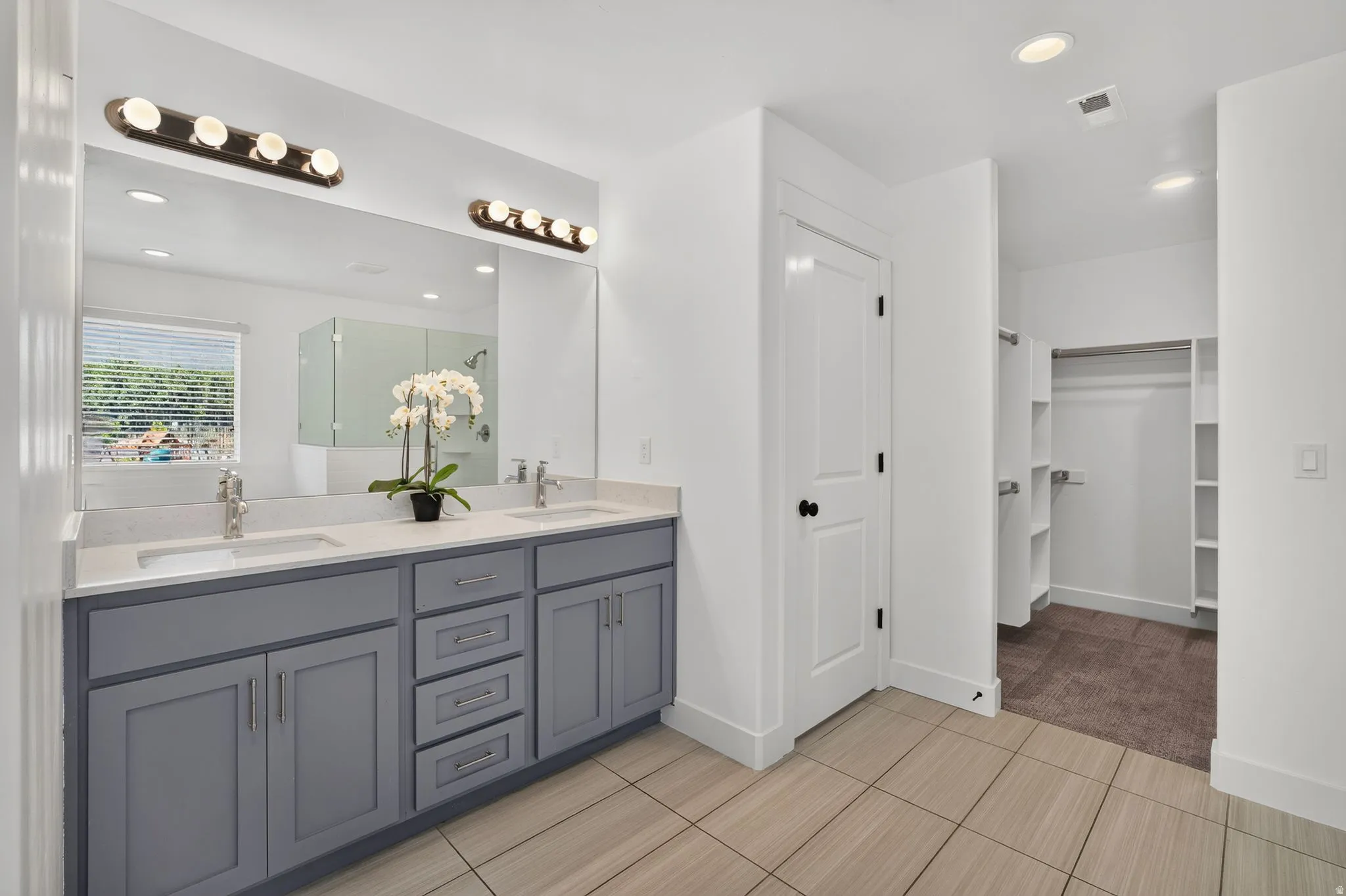Dual vanity with light gray cabinetry, integrated sinks, and polished chrome fixtures