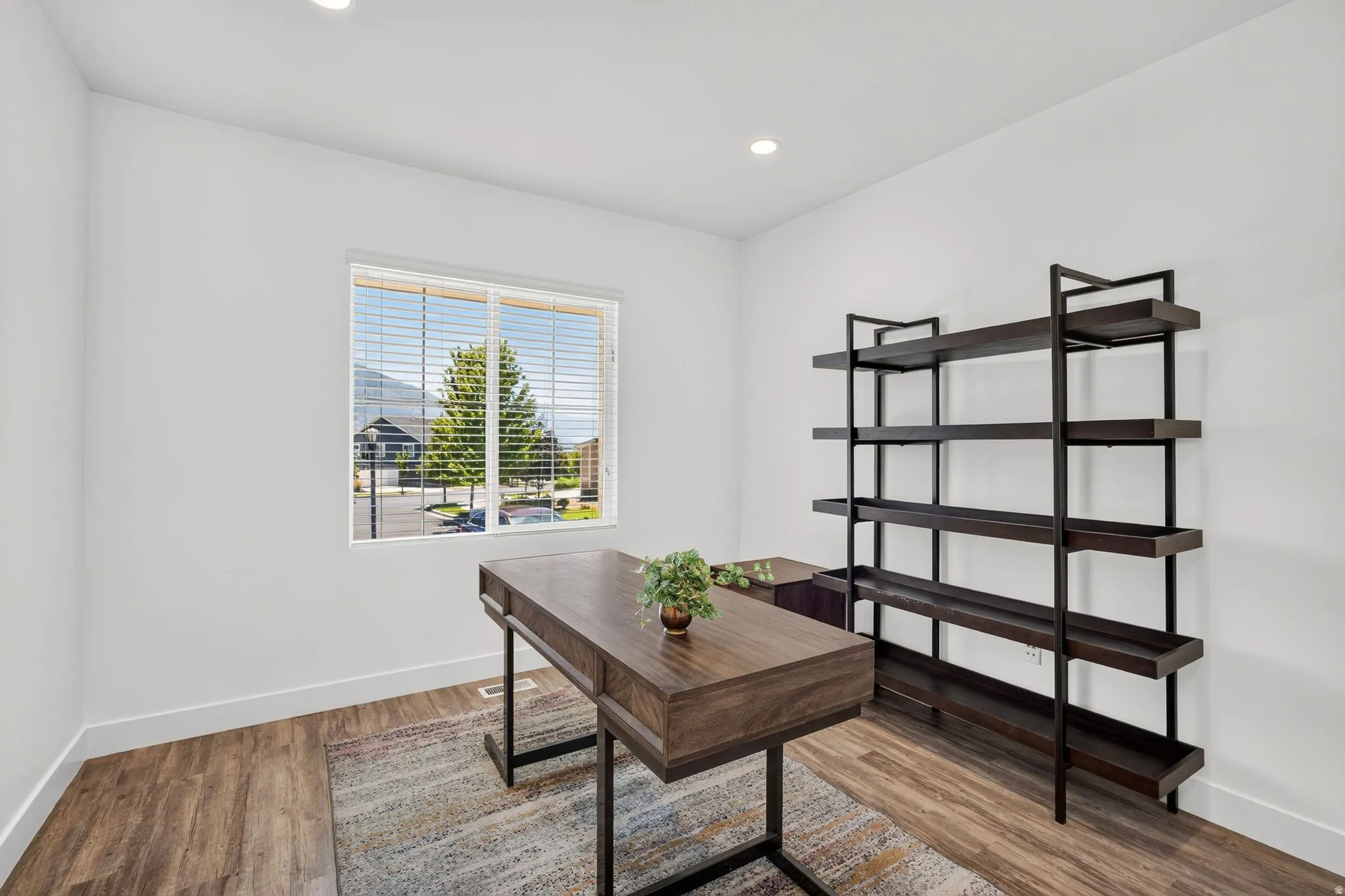 Bright room featuring a large window, recessed lighting, wood-finish flooring, and white baseboards