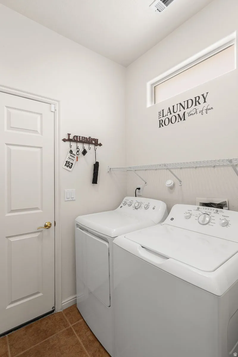 Dedicated laundry area with a white paneled door, ceramic tile flooring, and a high transom window