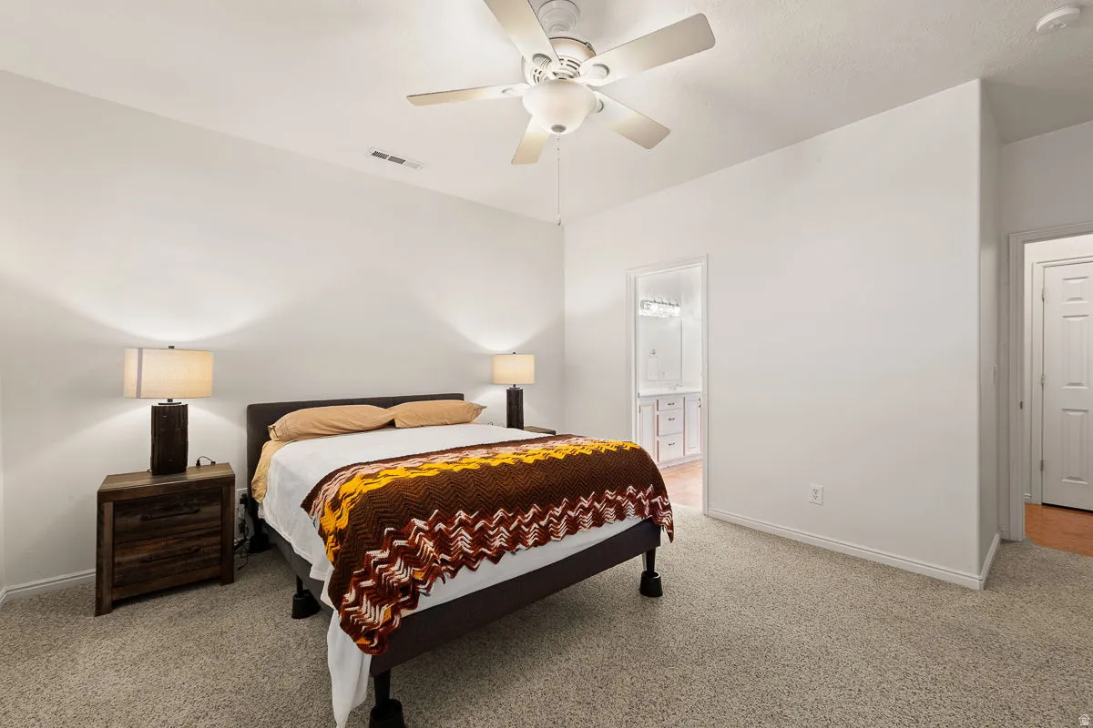 Carpeted room featuring white walls and a ceiling fan with light fixture
