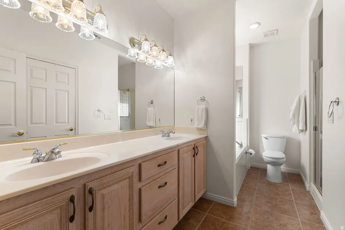 Bathroom vanity featuring dual sinks with individual faucets, ample counter space, and integrated storage cabinetry
