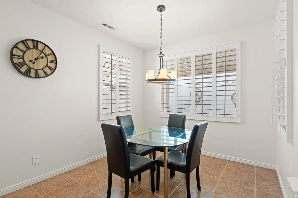 Dining area featuring a contemporary chandelier, multiple windows with white plantation shutters, and light-toned walls
