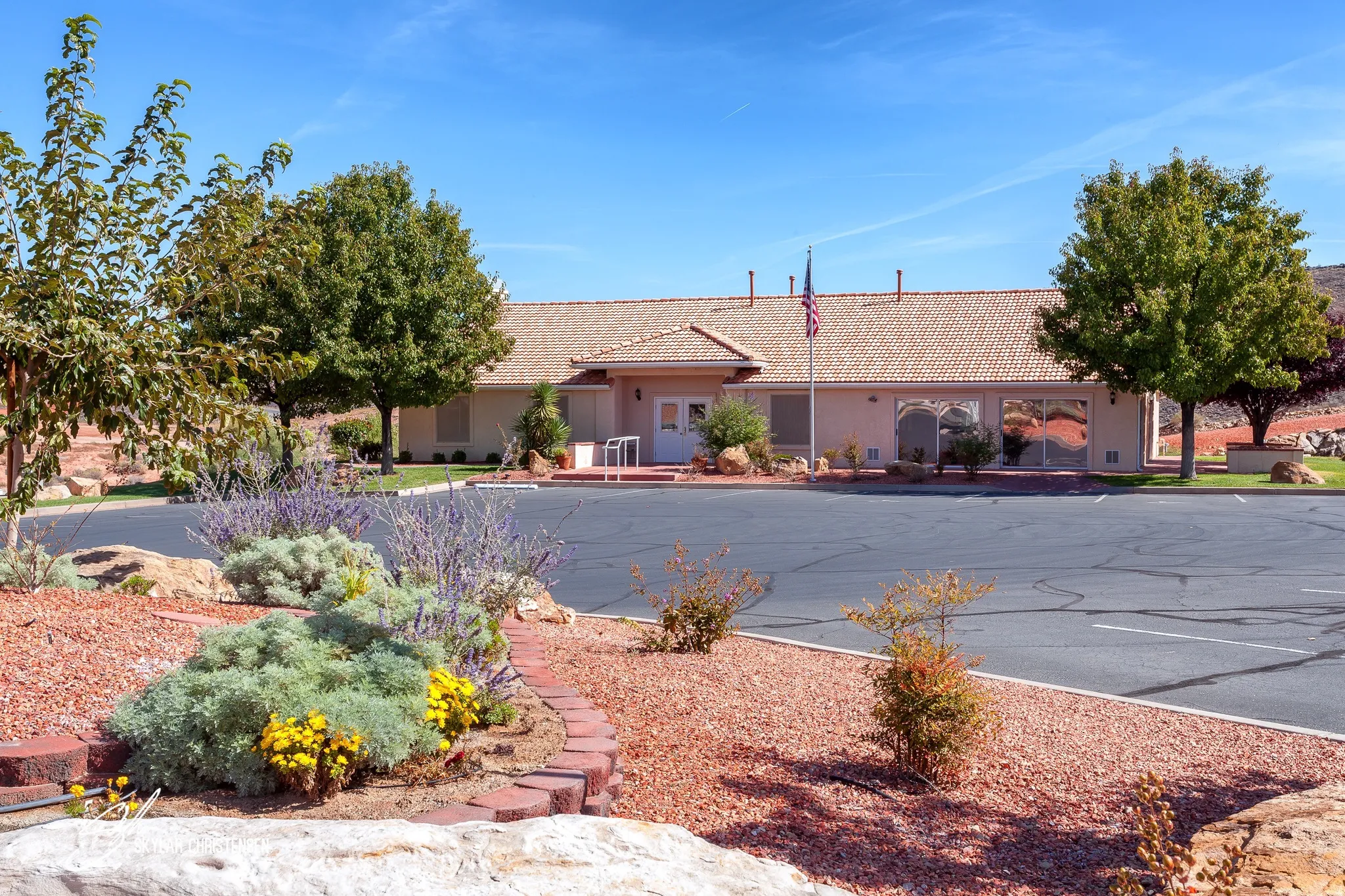 Southwestern-style building with a tile roof and a spacious parking area