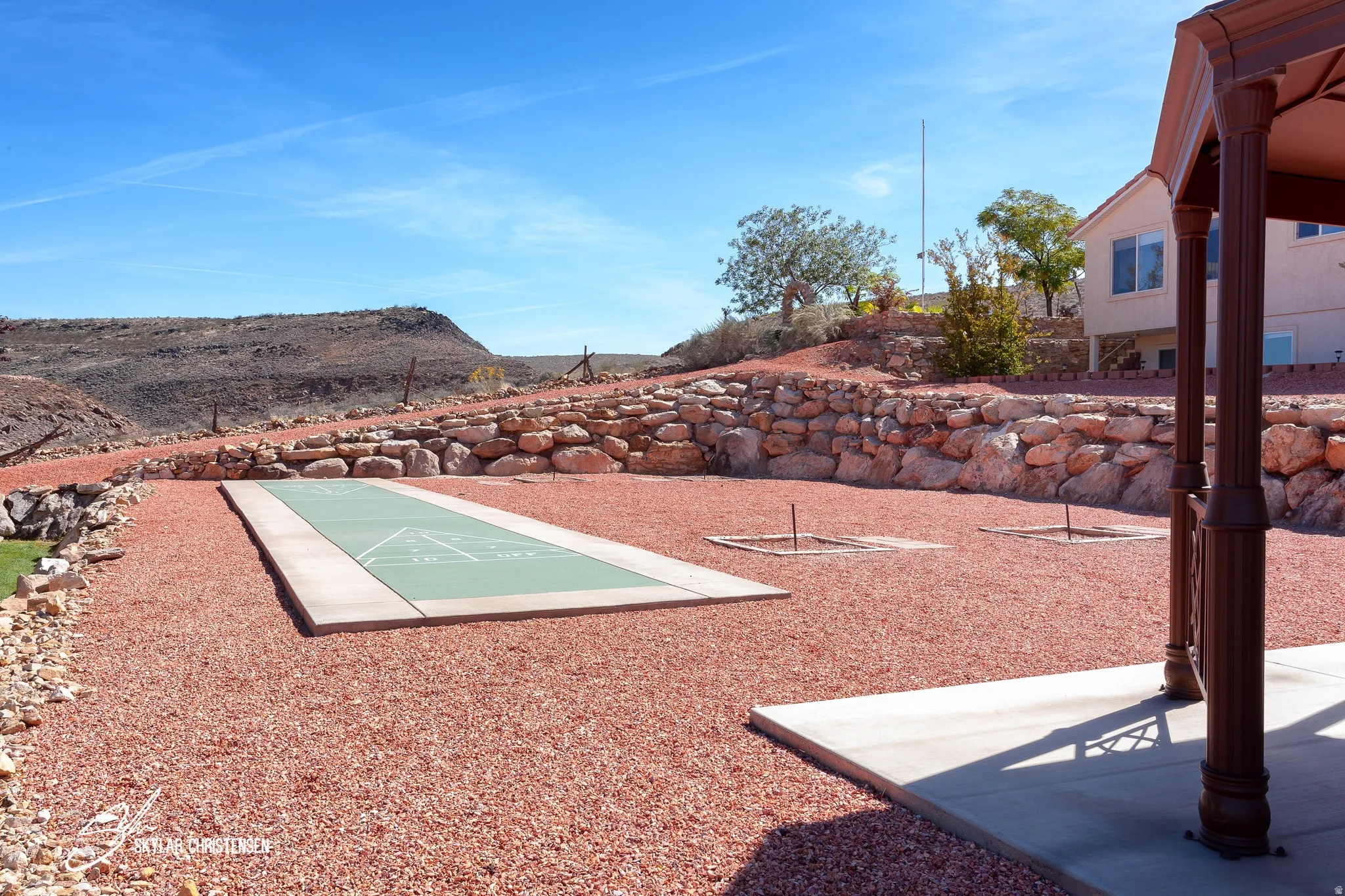 Expansive outdoor area featuring a shuffleboard court, two horseshoe pits, and red crushed rock landscaping