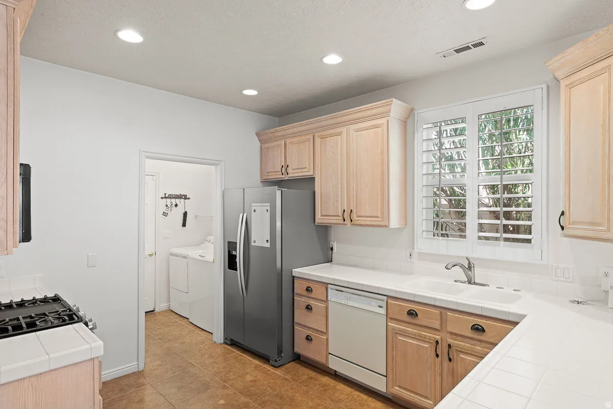 Kitchen featuring light wood cabinetry and a tile countertop