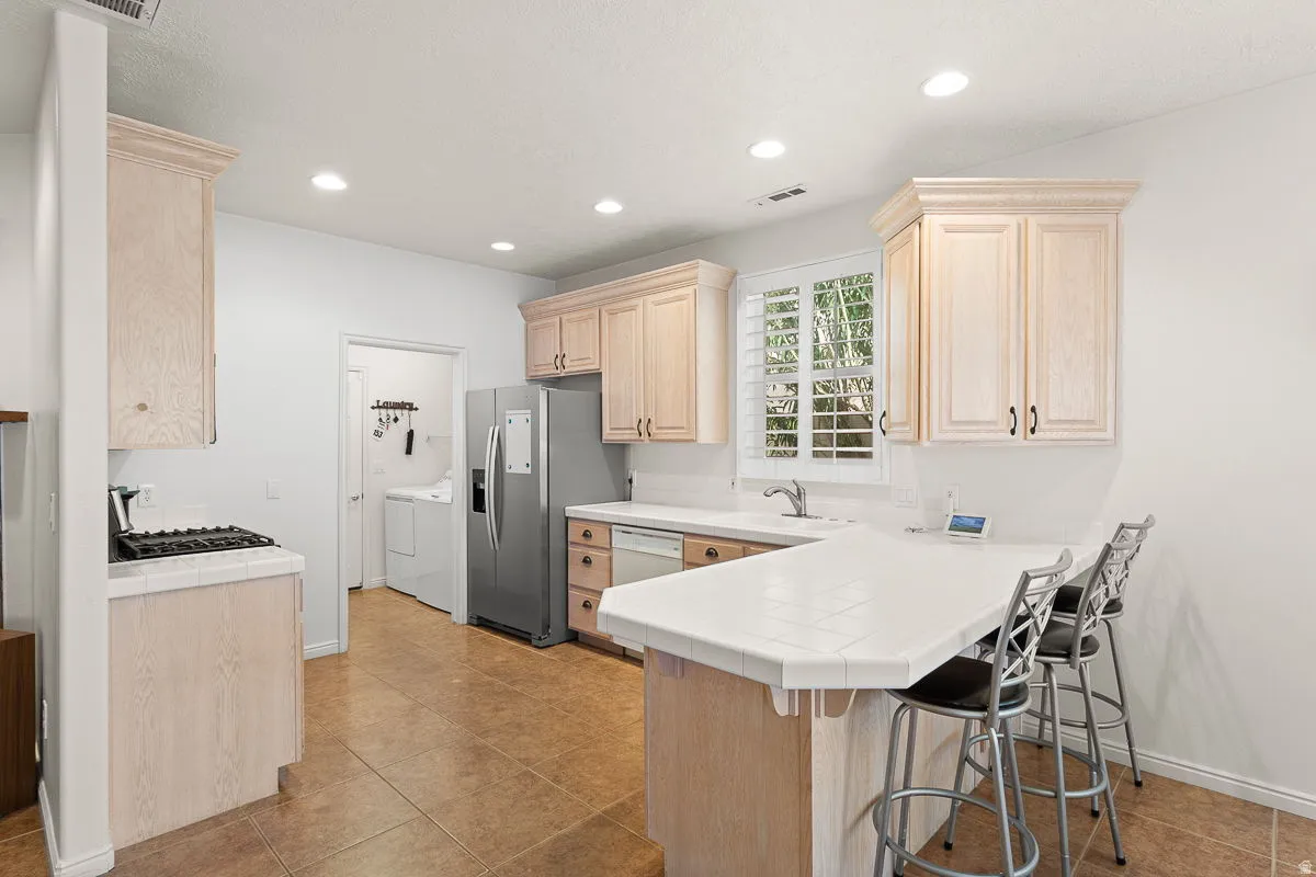 Kitchen featuring ceramic tile flooring, light wood-finish cabinetry, a gas cooktop, recessed lighting, and a window with plantation shutters