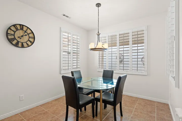 Dining area featuring a contemporary chandelier, multiple windows with white plantation shutters, and light-toned walls