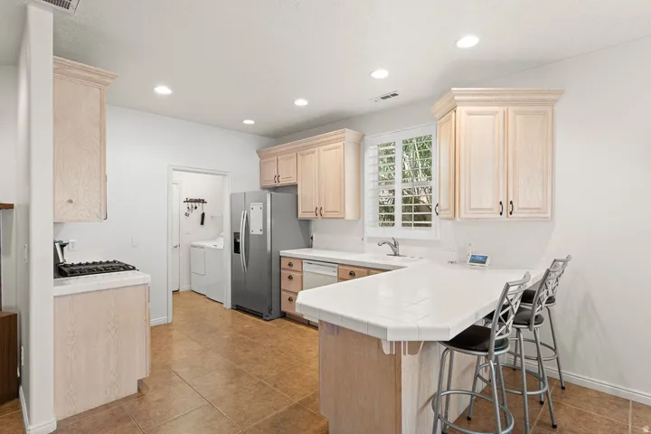 Kitchen featuring ceramic tile flooring, light wood-finish cabinetry, a gas cooktop, recessed lighting, and a window with plantation shutters