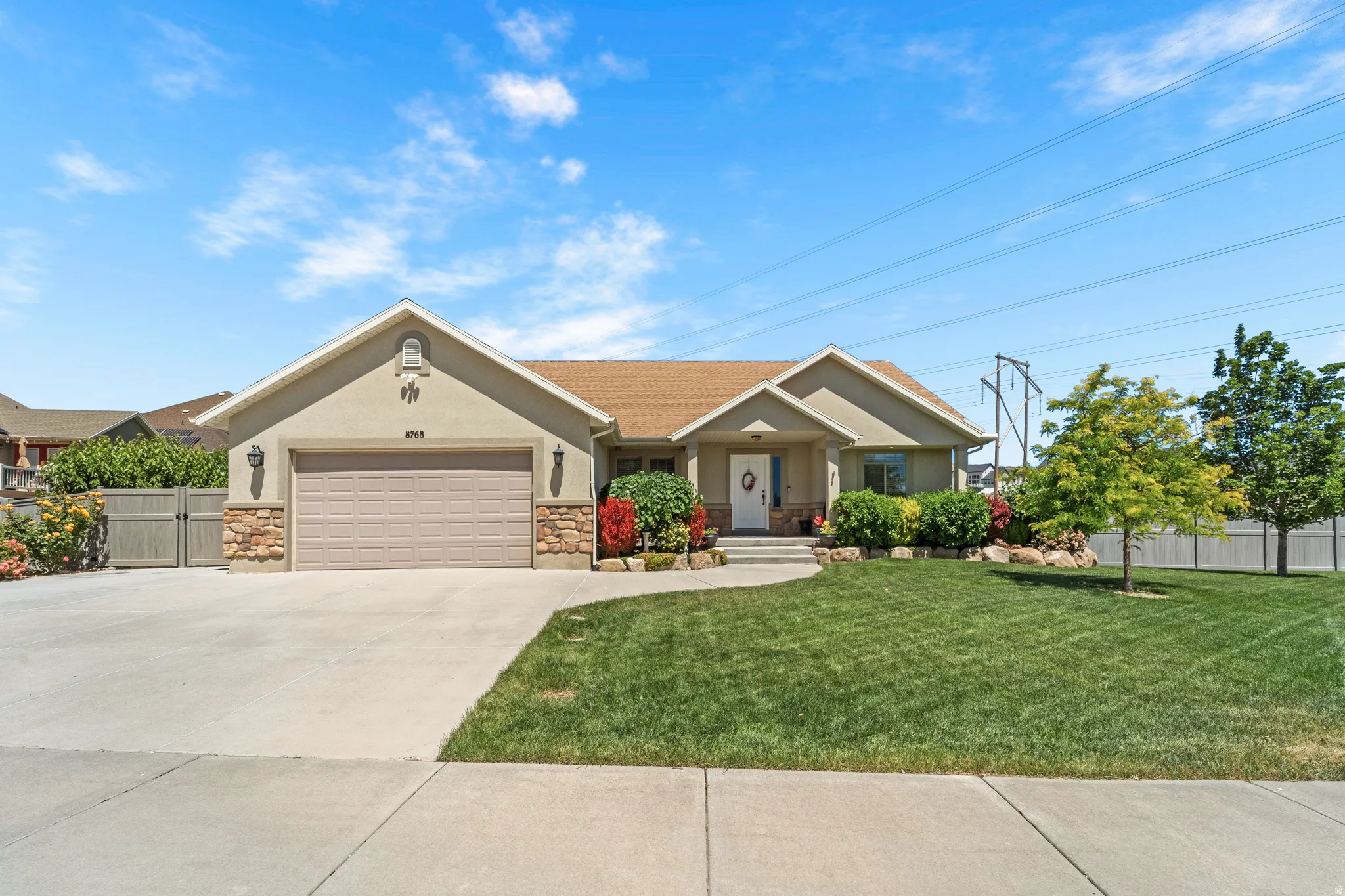 Beige stucco exterior with stone accents, featuring an attached garage and a concrete driveway