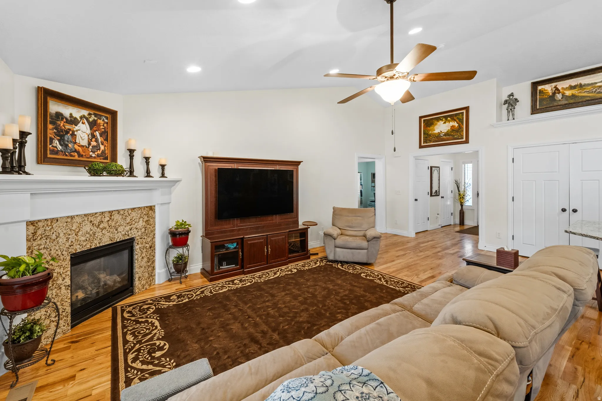 Spacious living area featuring light wood-finish flooring, a vaulted ceiling, and recessed lighting