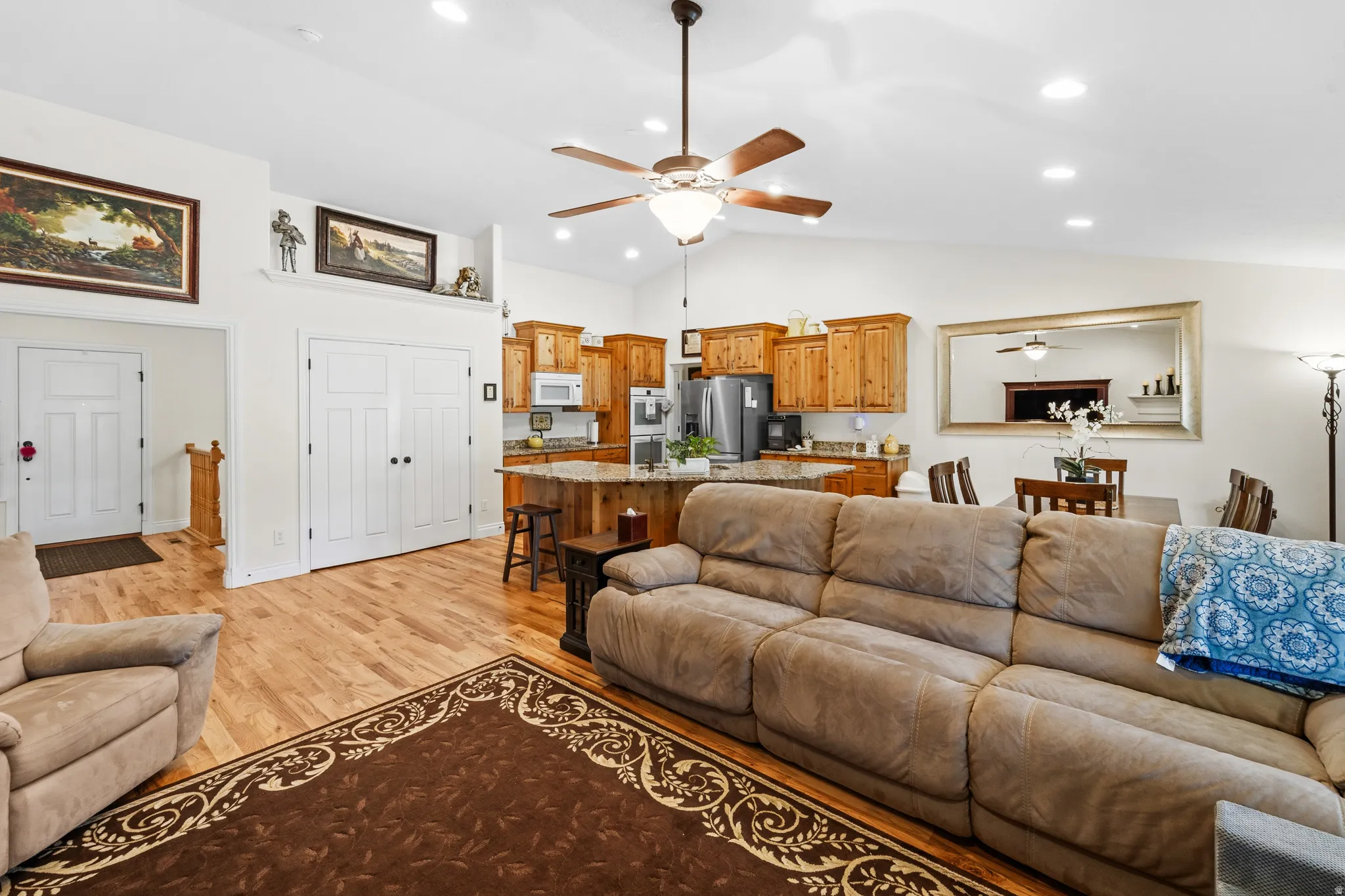 Vaulted ceiling living area with wood-finish flooring, recessed lighting, and a ceiling fan