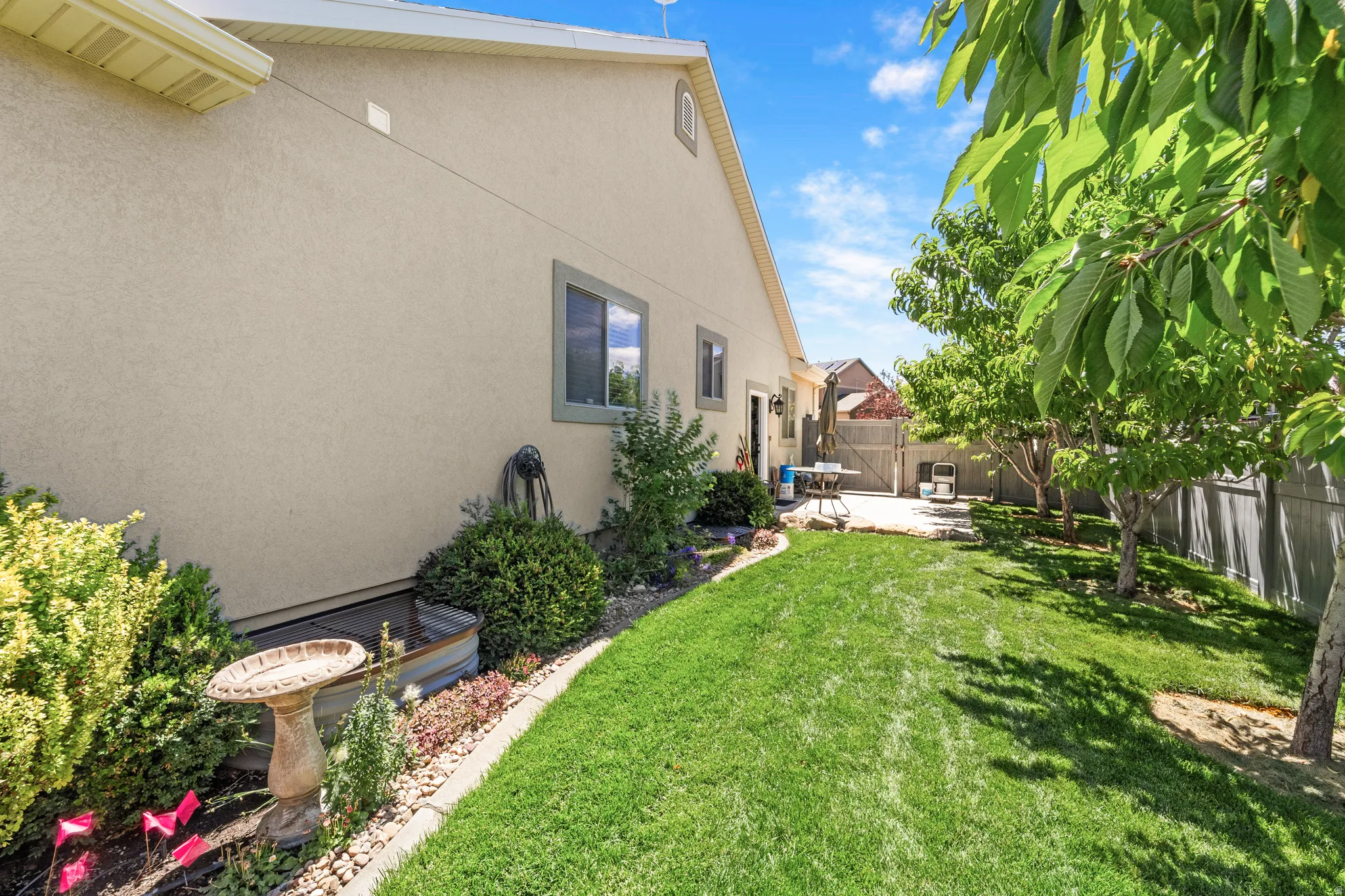 Expansive rear yard featuring a manicured lawn, established trees, and a concrete patio