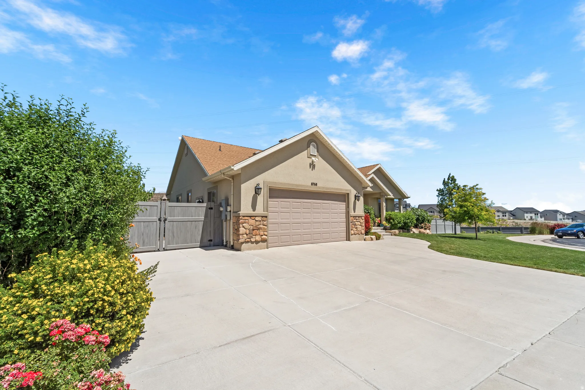 The exterior features a stucco finish, stone accents, and an attached two-car garage with a panel door