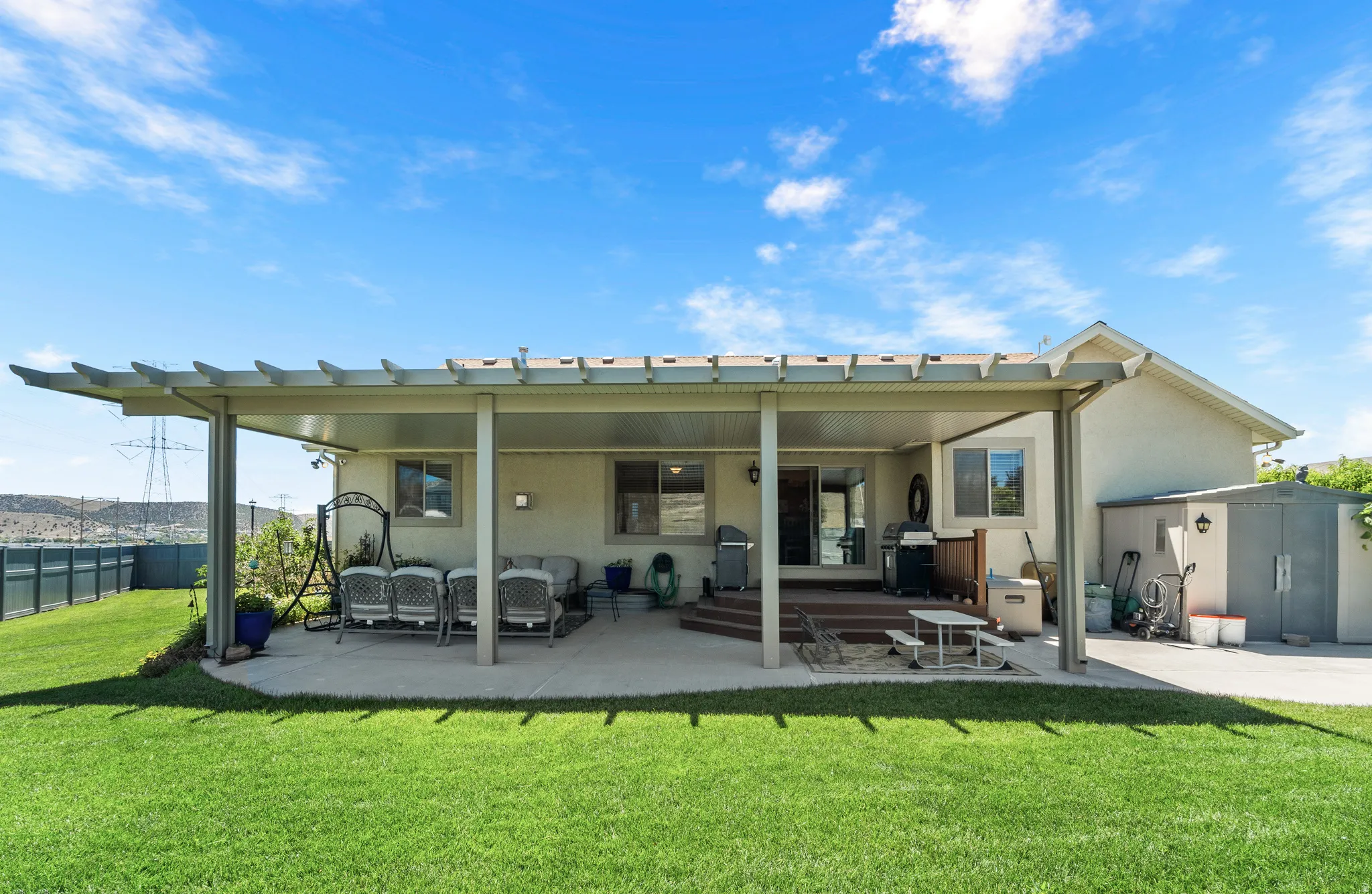 Expansive concrete patio with a full-length covered pergola and step-down decking