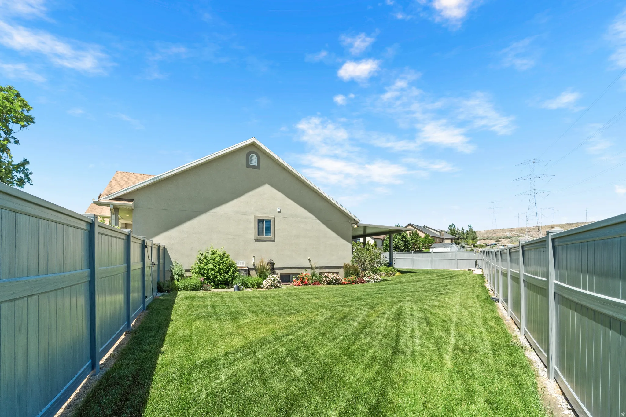 Expansive backyard with a manicured lawn, established landscaping, and perimeter fencing
