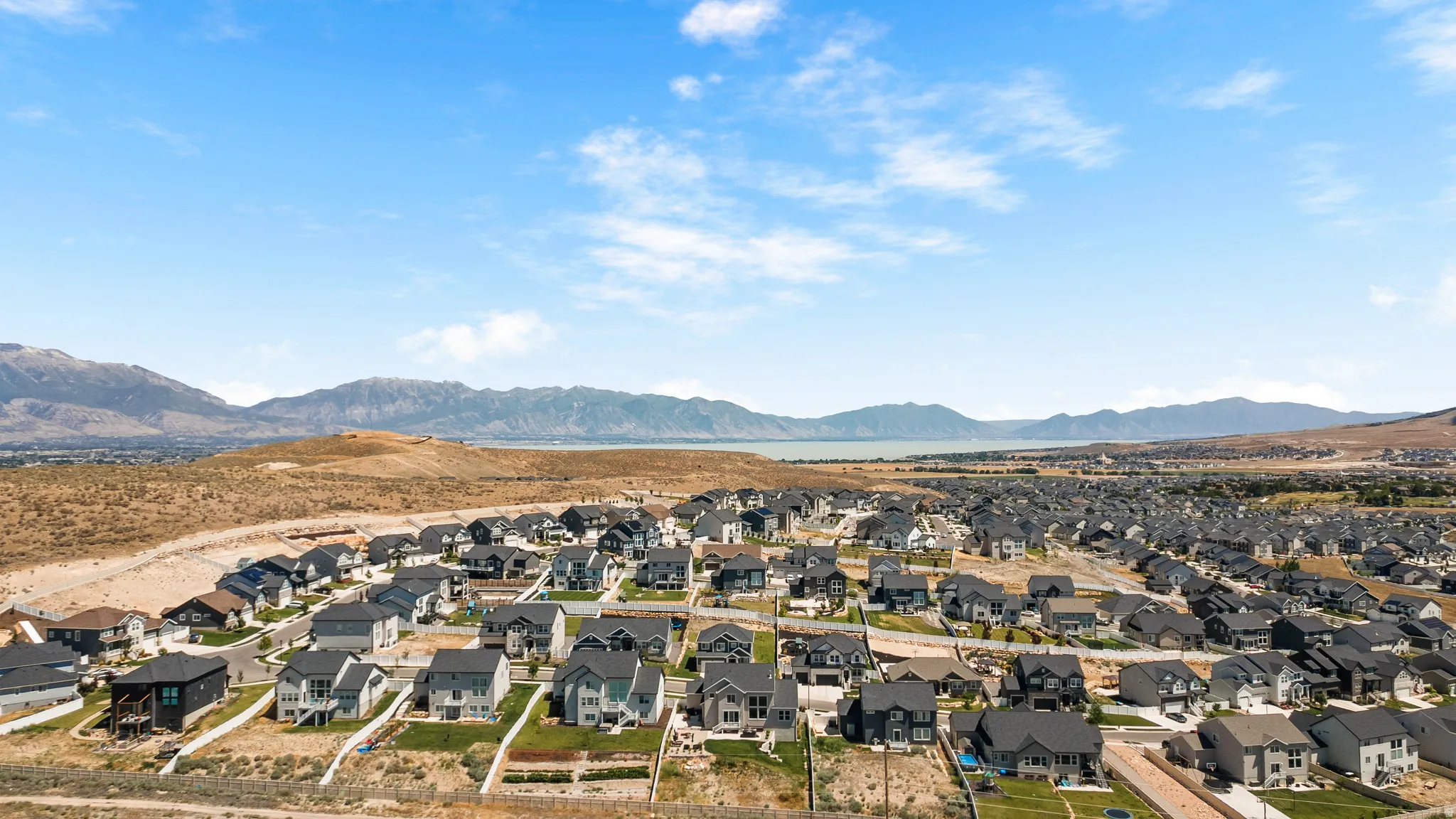 Expansive residential community featuring a variety of single-family homes, clear skies, and distant mountain ranges