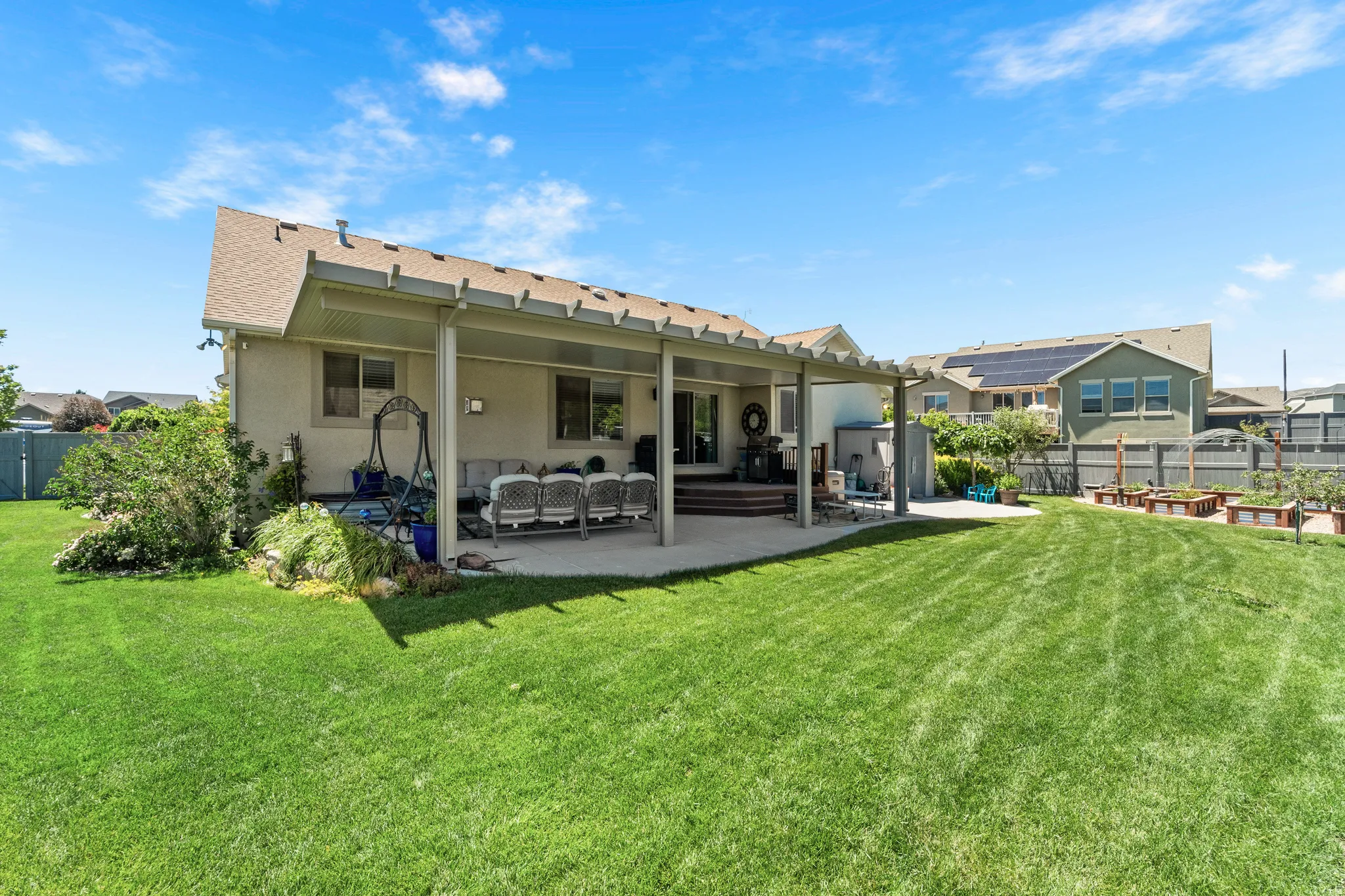 Expansive green lawn with a covered patio featuring a slatted pergola