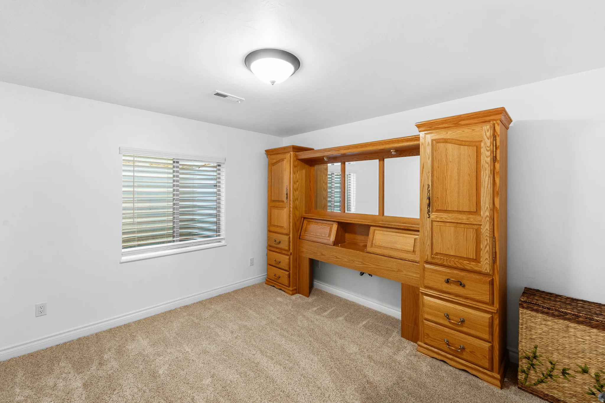 Carpeted room featuring a ceiling-mounted light fixture and a window with horizontal blinds