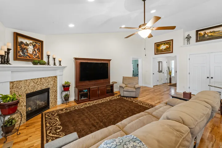 Spacious living area featuring light wood-finish flooring, a vaulted ceiling, and recessed lighting