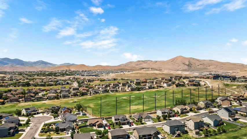Aerial perspective showcasing a residential community with a manicured green space, surrounded by mountainous terrain
