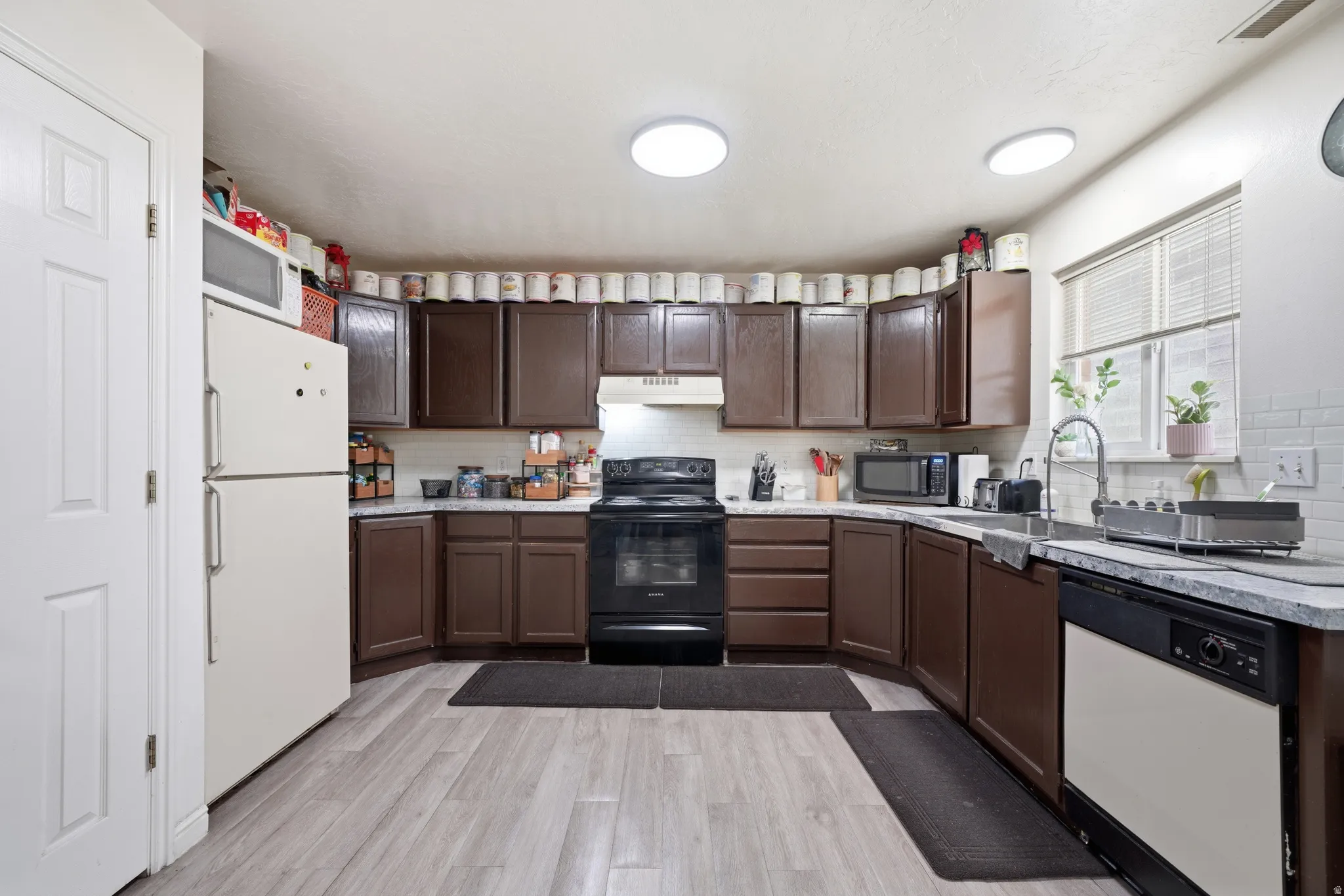 Kitchen featuring wood-finish flooring, dark wood cabinetry, and light-toned countertops