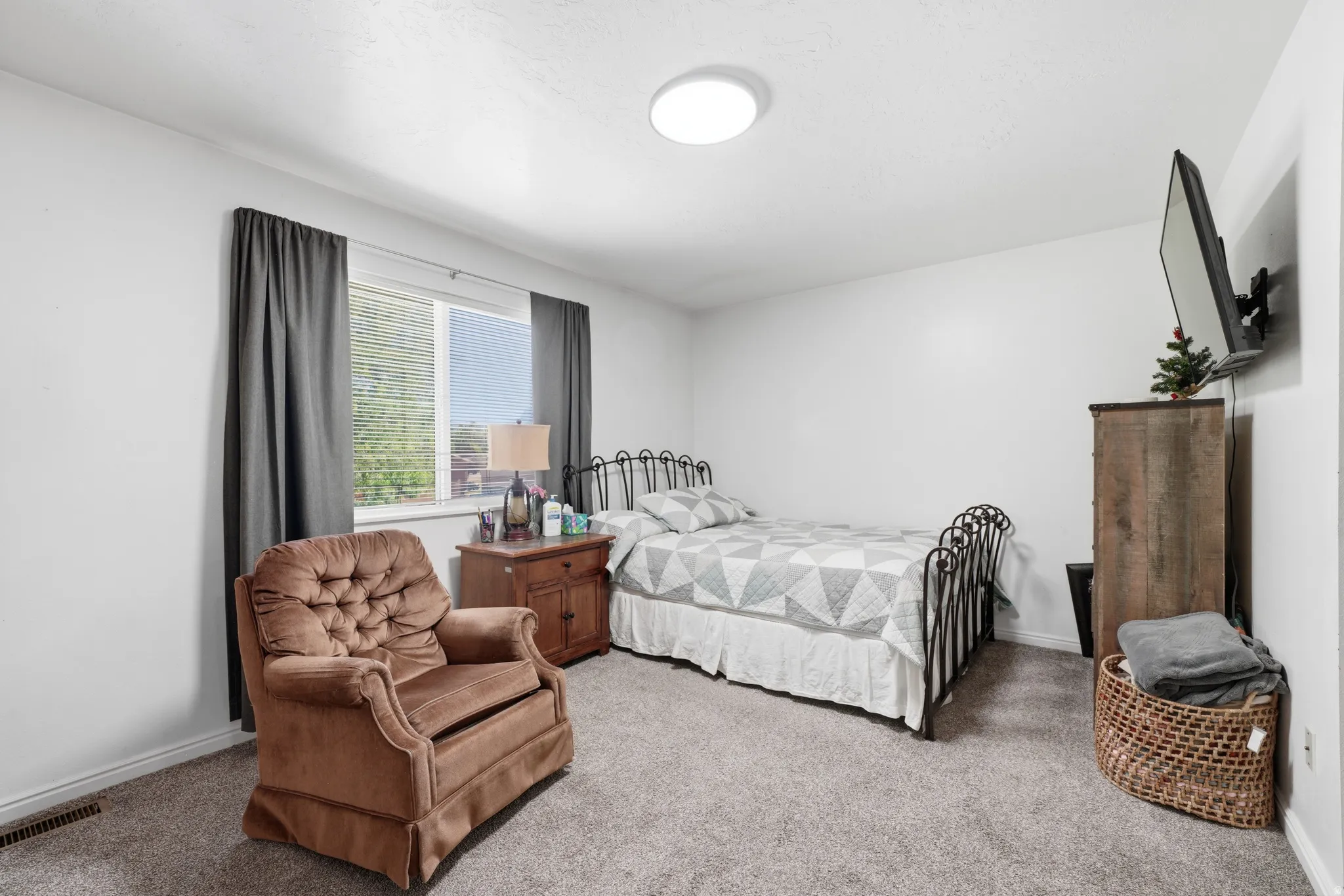 Carpeted room featuring a window with blinds, white walls, and a ceiling-mounted light fixture