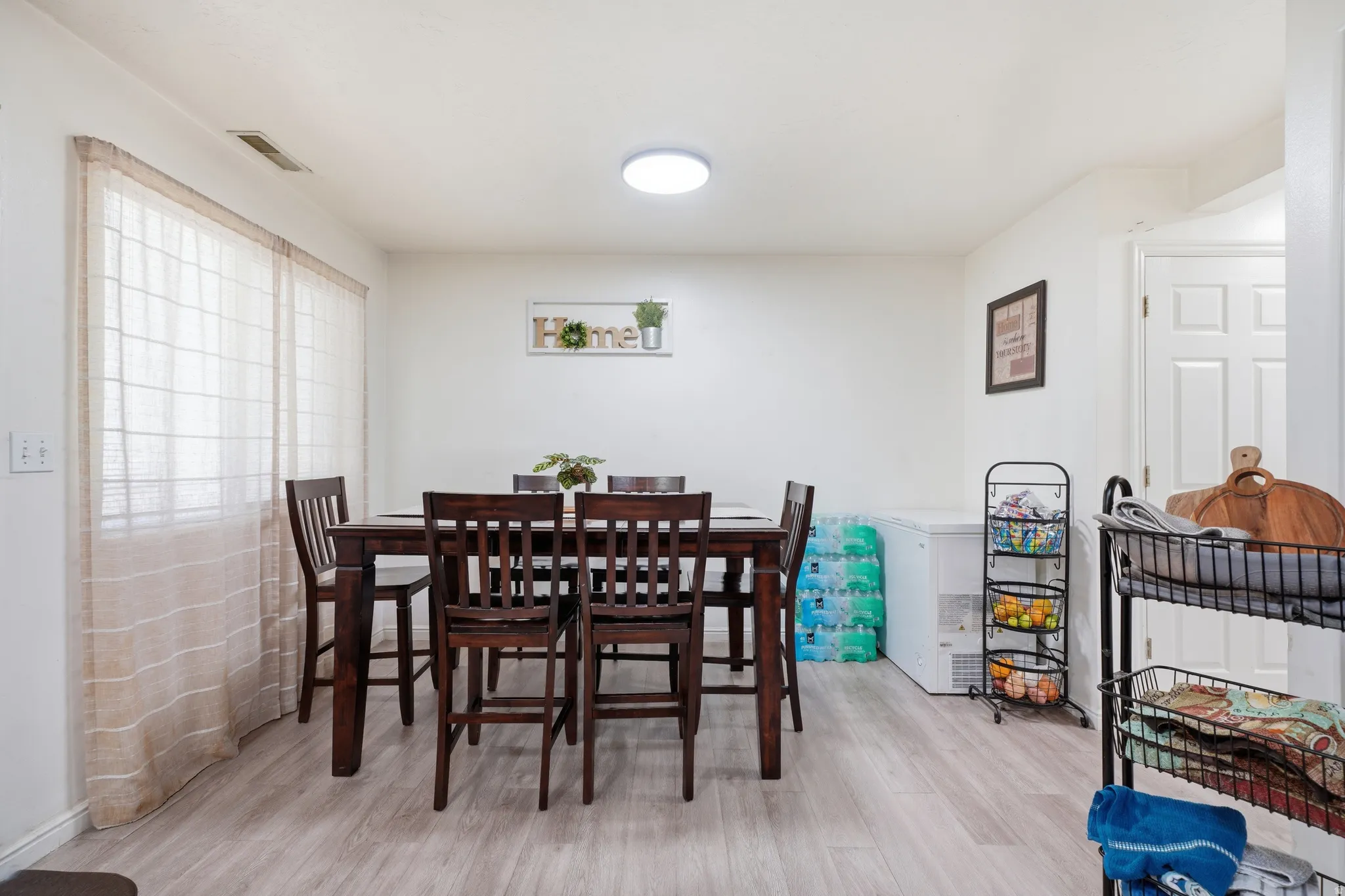 Dining area featuring wood-finish flooring, white walls, and a visible ceiling light fixture