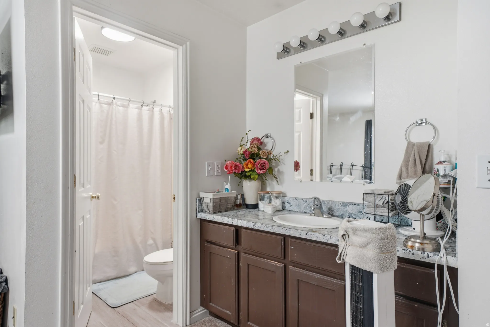 Bathroom vanity featuring a single sink, an integrated backsplash, and dark cabinetry