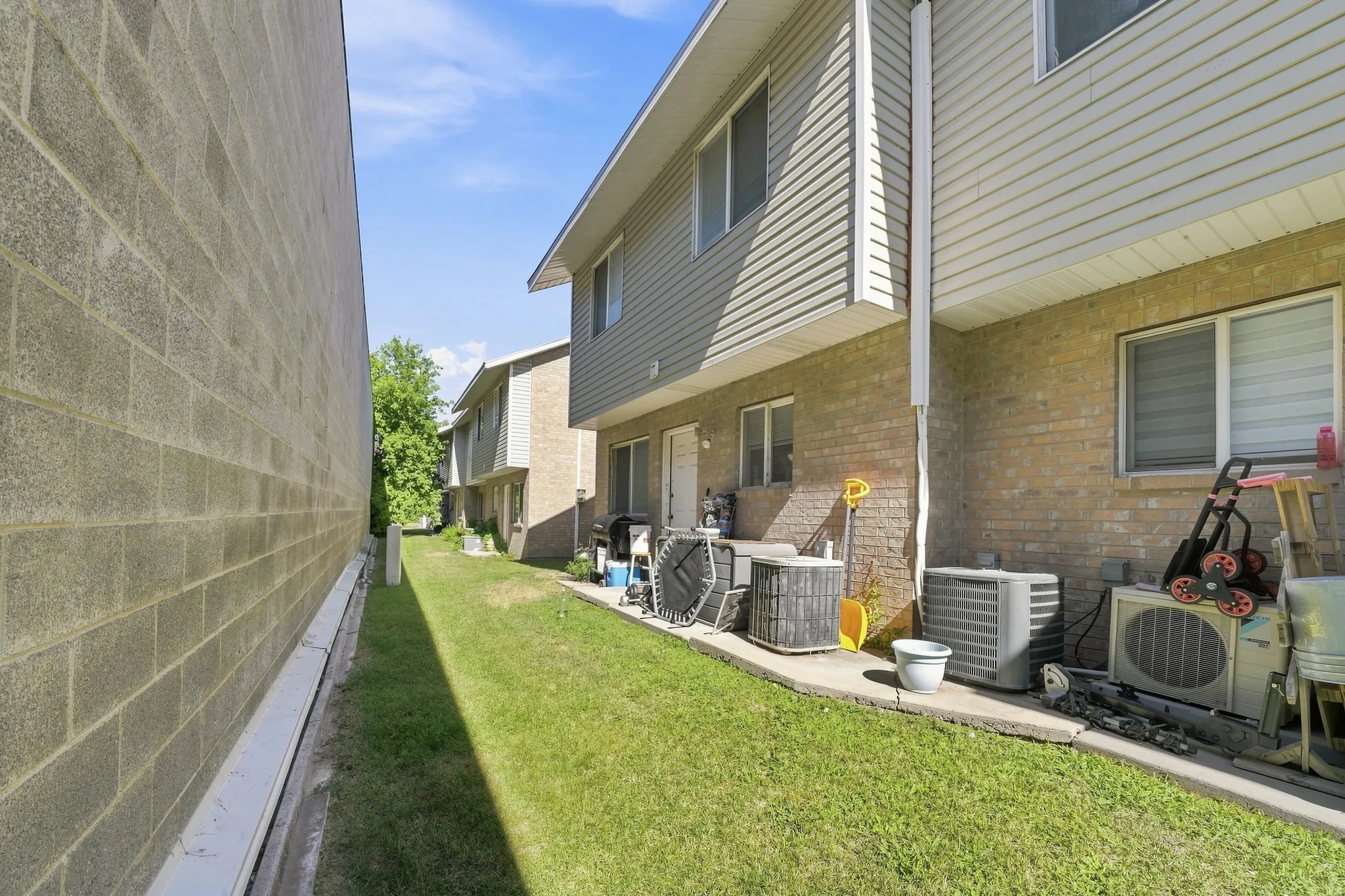 Exterior featuring brick and vinyl siding, multiple windows, and a grassy perimeter