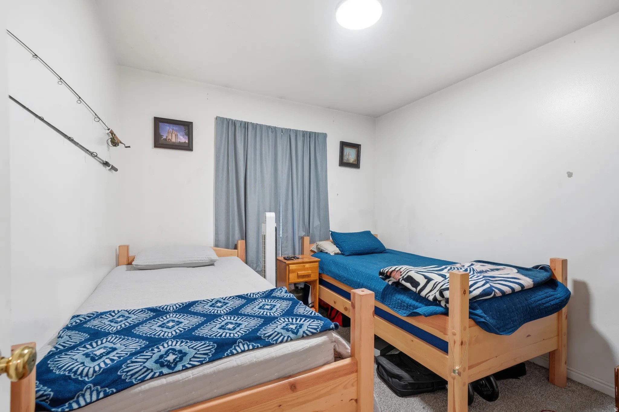 Bedroom featuring a window with blue drapes, white walls, and a ceiling-mounted light fixture