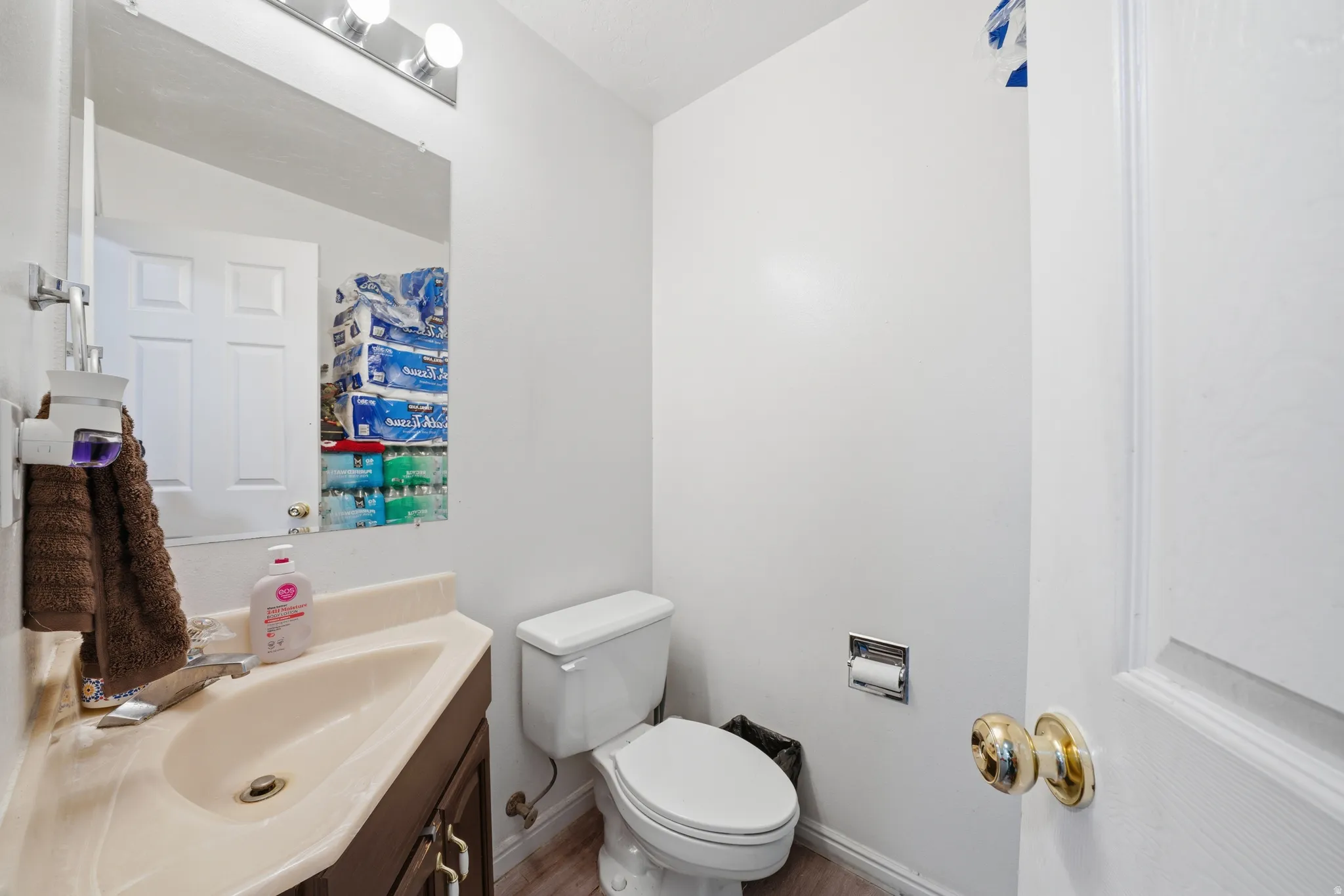 Compact bathroom featuring a vanity with an integrated sink, wood-finish cabinetry, and a mirrored wall cabinet with overhead lighting