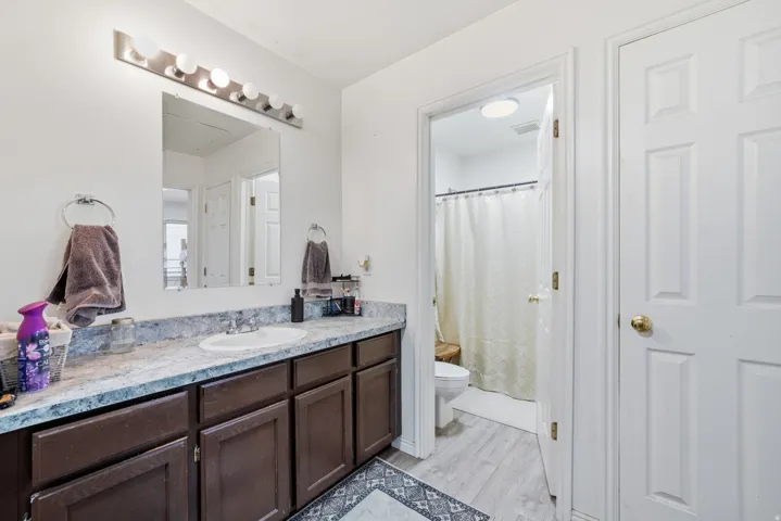 Vanity with an integrated sink, stone-finish countertop, and dark wood-finish cabinetry
