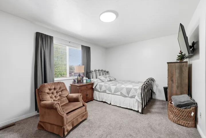 Carpeted room featuring a window with blinds, white walls, and a ceiling-mounted light fixture