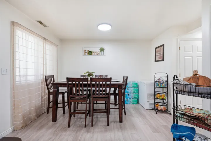 Dining area featuring wood-finish flooring, white walls, and a visible ceiling light fixture