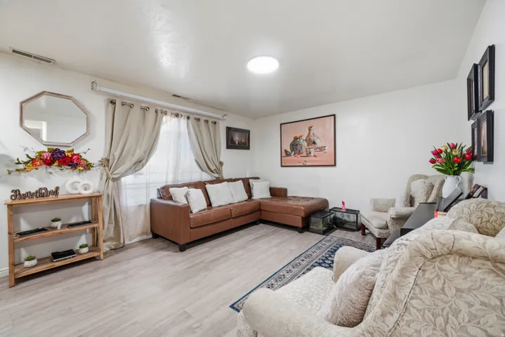 Spacious living area featuring light wood-finish flooring and white walls